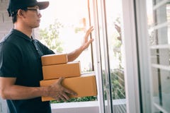 Young asian courier is using the hand of the knock at the door to deliver the goods royalty free stock photos Young asian courier is using the hand of the knock at the door to deliver the goods royalty free stock photos