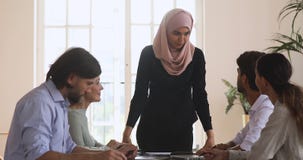 Young asian islamic female team leader holding meeting with colleagues.