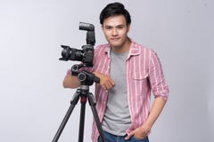 Young asian photographer holding digital camera, while working i Stock Photography Young asian photographer holding digital camera, while working i Stock Photography