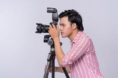 Young asian photographer holding digital camera, while working i Royalty Free Stock Photography Young asian photographer holding digital camera, while working i Royalty Free Stock Photography