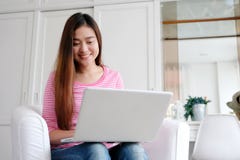 Young asian woman using laptop computer in casual while sitting in white room at home background, people and technology, royalty free stock photos Young asian woman using laptop computer in casual while sitting in white room at home background, people and technology, royalty free stock photos