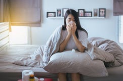 Young Asian Woman With Cold Blowing And Runny Nose On Bed,sick Female Sneezing Stock Photography