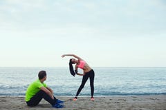 Young athletic girl with a beautiful figure warming up before running her boyfriend looking at her royalty free stock image Young athletic girl with a beautiful figure warming up before running her boyfriend looking at her royalty free stock image