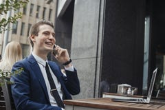 Young attractive brunette businessman talking by mobile phone and smiling. royalty free stock photos Young attractive brunette businessman talking by mobile phone and smiling. royalty free stock photos