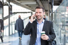 Young Attractive Business Man Using Smartphone While Drinking Co Royalty Free Stock Photos