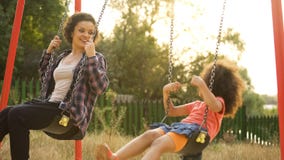 Young babysitter playing with carefree kid, swinging outdoor at child playground stock images Young babysitter playing with carefree kid, swinging outdoor at child playground stock images