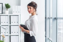 Young beautiful businesswoman using tablet with internet in office, reading and sending messages, smiling, looking at royalty free stock photo Young beautiful businesswoman using tablet with internet in office, reading and sending messages, smiling, looking at royalty free stock photo