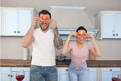 Young beautiful couple fool in the kitchen. They keep bits of Bulgarian pepper around their eyes and laugh royalty free stock images Young beautiful couple fool in the kitchen. They keep bits of Bulgarian pepper around their eyes and laugh royalty free stock images