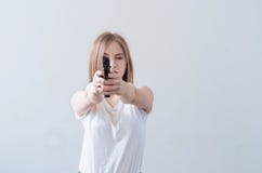 Young beautiful girl holding a gun in her hands. Aims at the camera