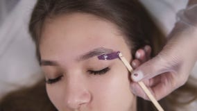 Young beautiful girl is lying on couch during eyebrowes treatment at studio beauty, beautician depilating and shaping stock video footage Young beautiful girl is lying on couch during eyebrowes treatment at studio beauty, beautician depilating and shaping stock video footage