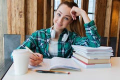Young beautiful student girl is doing her homework or preparing to the exams siting with books copybooks stock image Young beautiful student girl is doing her homework or preparing to the exams siting with books copybooks stock image