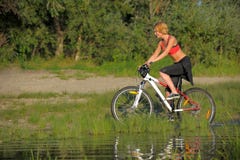 Young beautiful woman with bicycle going through water by the river Royalty Free Stock Images Young beautiful woman with bicycle going through water by the river Royalty Free Stock Images