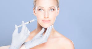 Young and beautiful woman having skin injections over blue background. Plastic surgery concept. stock images Young and beautiful woman having skin injections over blue background. Plastic surgery concept. stock images