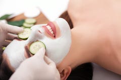 Young beautiful woman receiving clay facial mask in spa beauty salon. Skin care, Beauty treatments.