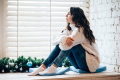 Young beautiful woman relaxing on window sill in christmas decor Royalty Free Stock Photos Young beautiful woman relaxing on window sill in christmas decor Royalty Free Stock Photos