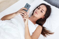 Young beautiful woman resting in bed with smartphone stock photography Young beautiful woman resting in bed with smartphone stock photography