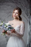 A young blonde bride in white wedding dress on a background of white walls and white tree in the background Stock Image A young blonde bride in white wedding dress on a background of white walls and white tree in the background Stock Image