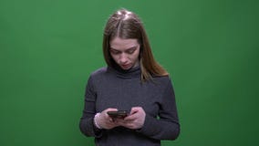 Young blonde businesswoman working attentively with smartphone isolated on green chromakey background. stock video footage Young blonde businesswoman working attentively with smartphone isolated on green chromakey background. stock video footage