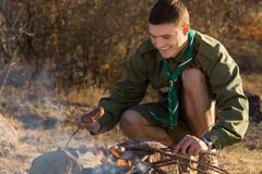 Young Boy Scout Cooking For Food On The Ground Royalty Free Stock Photos