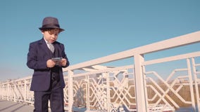 Young business boy in black suit and hat throwing money from bridge. Waste money stock video Young business boy in black suit and hat throwing money from bridge. Waste money stock video