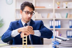 The young businessman building domino tower in office stock photo The young businessman building domino tower in office stock photo