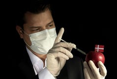 Young businessman injecting chemicals into an apple with Danish royalty free stock images Young businessman injecting chemicals into an apple with Danish royalty free stock images