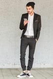 Young businessman stands by the wall and looks into the phone stock images Young businessman stands by the wall and looks into the phone stock images