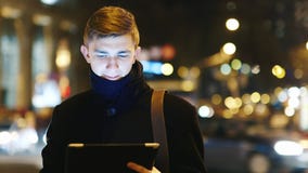 Young businessman with the tablet against the night traffic stock footage Young businessman with the tablet against the night traffic stock footage