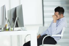 Young businessmen in stress. Sit in front of modern office computer, concept for hard work in an organization. stock image Young businessmen in stress. Sit in front of modern office computer, concept for hard work in an organization. stock image