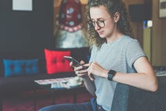 Young businesswoman hippest dressed in striped t-shirt sits on sofa in hotel lobby and uses smartphone.Girl is chatting royalty free stock images Young businesswoman hippest dressed in striped t-shirt sits on sofa in hotel lobby and uses smartphone.Girl is chatting royalty free stock images