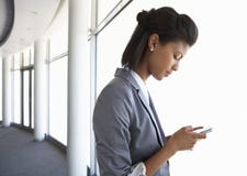 Young Businesswoman Standing In Corridor Of Modern Office Building Using Mobile Phone stock image Young Businesswoman Standing In Corridor Of Modern Office Building Using Mobile Phone stock image