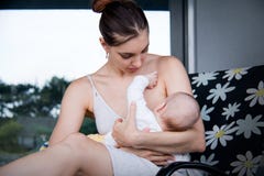 Young caring mother breastfeeding her little baby on grey house background royalty free stock photos Young caring mother breastfeeding her little baby on grey house background royalty free stock photos