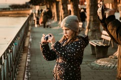 Young caucasian girl taking photo of the sunset at the border of a sea