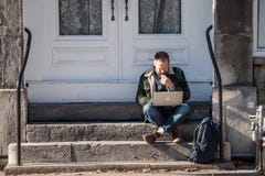 Young Caucasian Male, digital nomad, sitting and using his laptop, Apple Macbook, to get wifi internet connection in Old Montreal stock photo Young Caucasian Male, digital nomad, sitting and using his laptop, Apple Macbook, to get wifi internet connection in Old Montreal stock photo