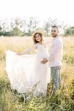 Young Couple, Caucasian Man And His Pregnant Wife In A Field. Happy Family Resting On The Wild Field Or Meadow In Summer Royalty Free Stock Photo