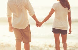 Young Couple Holding Hands on the Beach at Sunset