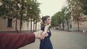 Young couple holding hands woman leading boyfriend walking in street stock footage Young couple holding hands woman leading boyfriend walking in street stock footage