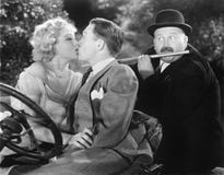 Young Couple Kissing Each Other Affectionately While A Man Is Playing Flute Royalty Free Stock Photography Young Couple Kissing Each Other Affectionately While A Man Is Playing Flute Royalty Free Stock Photography