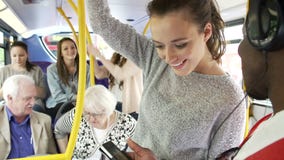 Young Couple Looking At Mobile Phone On Crowded Bus
