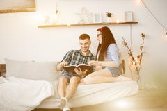 Young couple in love reading on the sofa. A pregnant woman and a happy husband. Man takes hands on woman`s belly Studio Stock Photo Young couple in love reading on the sofa. A pregnant woman and a happy husband. Man takes hands on woman`s belly Studio Stock Photo