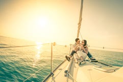 Young couple in love on sail boat with champagne at sunset