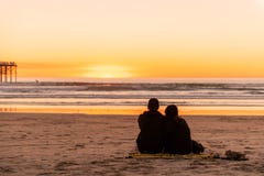 Young couple sitting on the beach watching golden sunset royalty free stock photos Young couple sitting on the beach watching golden sunset royalty free stock photos