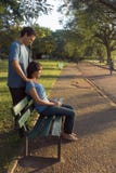 Young Couple Sitting On A Park Bench - Vertical Stock Photo