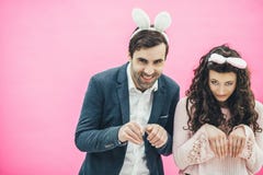 Young couple standing on pink background. With a bunny ears on the head. Beautiful, macho or boyfriend and cute girl stock photo Young couple standing on pink background. With a bunny ears on the head. Beautiful, macho or boyfriend and cute girl stock photo