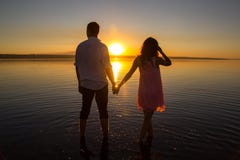 Young couple is walking in the water on summer beach. Sunset over the sea.Two silhouettes against the sun. Just married couple royalty free stock photo Young couple is walking in the water on summer beach. Sunset over the sea.Two silhouettes against the sun. Just married couple royalty free stock photo