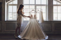 Young Cute Brunette Bride Looking At Her Wedding Dress. Royalty Free Stock Images Young Cute Brunette Bride Looking At Her Wedding Dress. Royalty Free Stock Images
