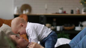 Young cute girl playing with her son on the bed. A young mother is playing with a baby on the bed. stock video footage Young cute girl playing with her son on the bed. A young mother is playing with a baby on the bed. stock video footage