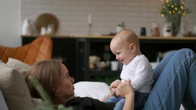 Young cute girl playing with her son on the bed. A young mother is playing with a baby on the bed. stock video Young cute girl playing with her son on the bed. A young mother is playing with a baby on the bed. stock video