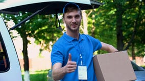 Young delivery man holding parcel, showing thumbs up, fast shipping service royalty free stock images Young delivery man holding parcel, showing thumbs up, fast shipping service royalty free stock images