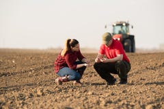 Young farmers examing planted wheat while tractor is plowing fi stock photos Young farmers examing planted wheat while tractor is plowing fi stock photos